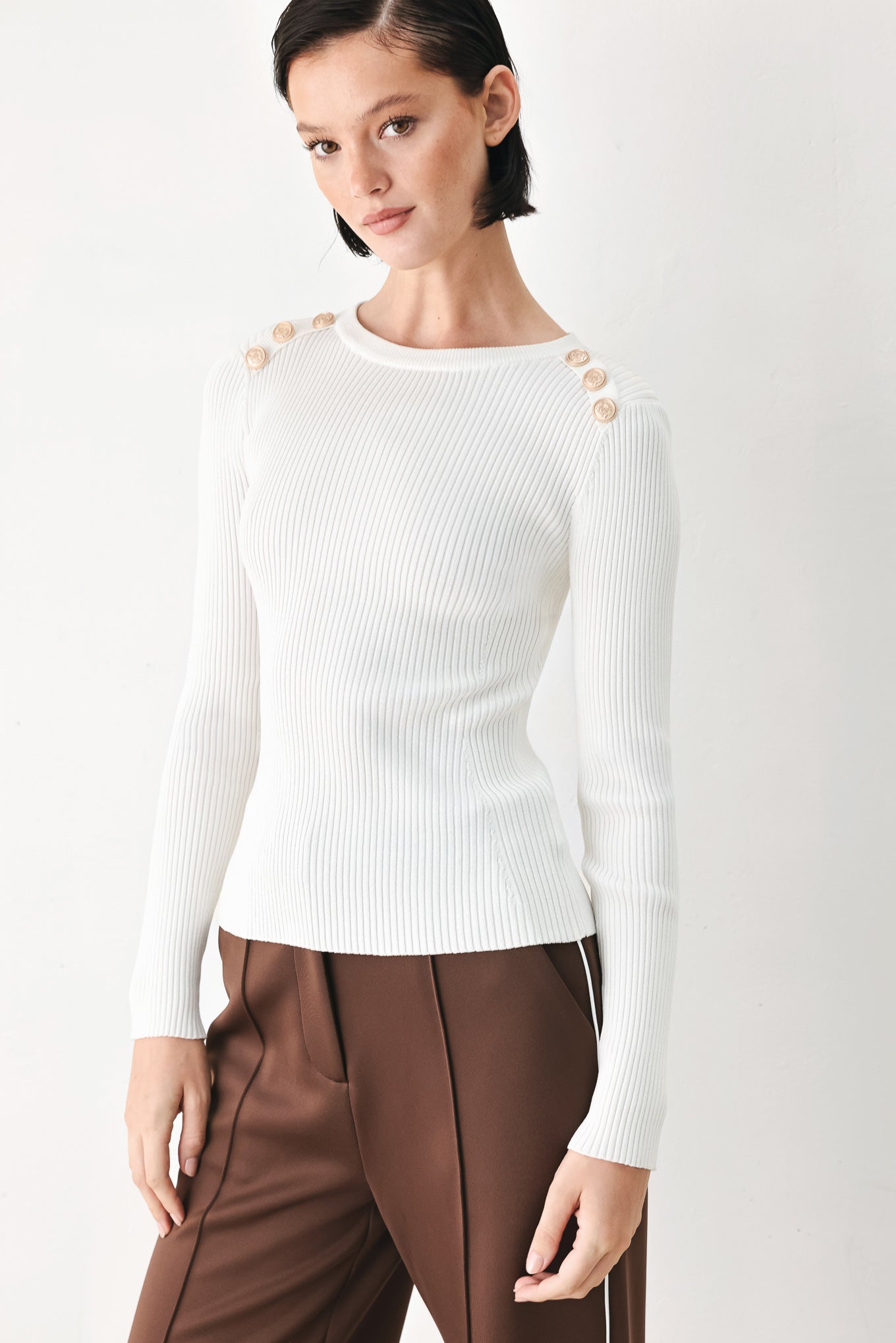 A woman modeling a white ribbed long-sleeve sweater with decorative gold buttons on the shoulders | FREEMARKET