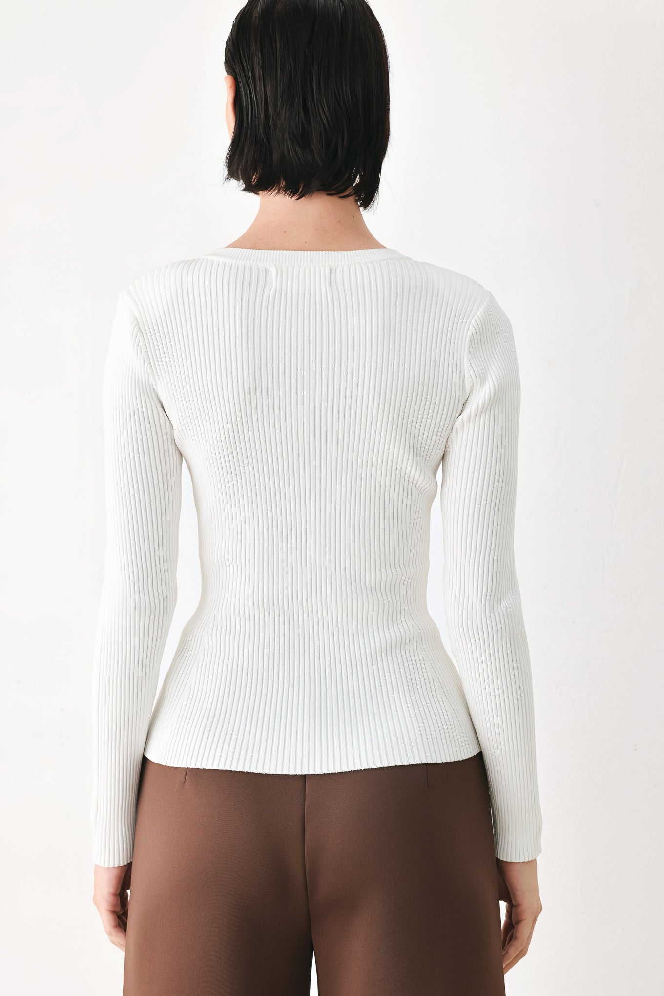 A woman modeling a white ribbed long-sleeve sweater with decorative gold buttons on the shoulders | FREEMARKET