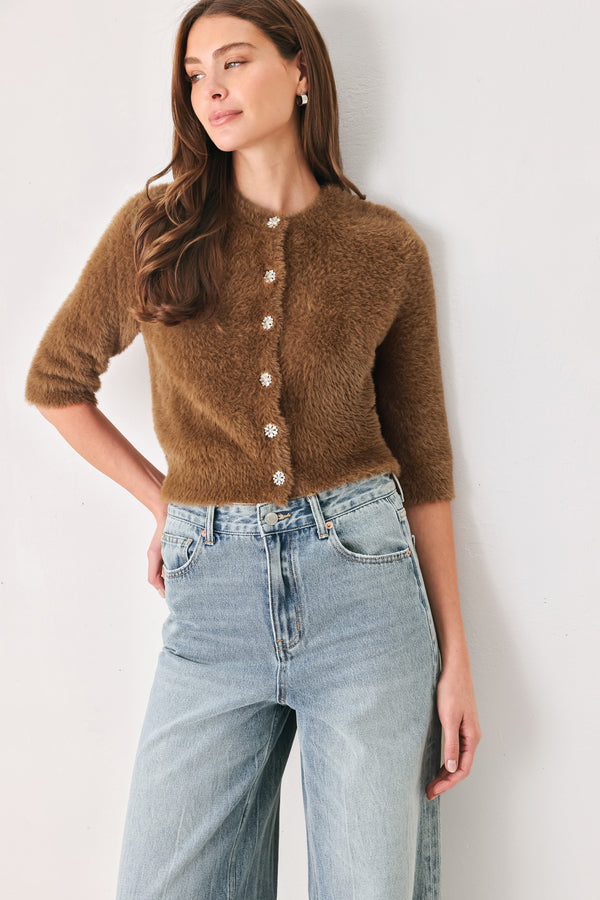 A woman wearing a brown fuzzy cropped cardigan with decorative silver buttons down the front | FREEMARKET