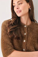 A woman wearing a brown fuzzy cropped cardigan with decorative silver buttons down the front | FREEMARKET