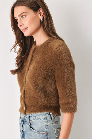 A woman wearing a brown fuzzy cropped cardigan with decorative silver buttons down the front | FREEMARKET
