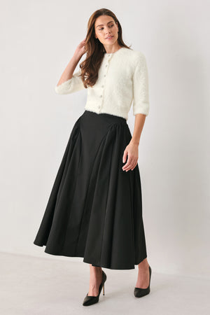 A woman wearing an off white fuzzy cropped cardigan with decorative silver buttons down the front | FREEMARKET