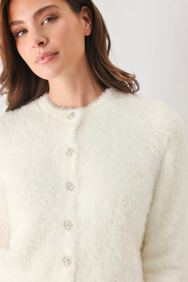 A woman wearing an off white fuzzy cropped cardigan with decorative silver buttons down the front | FREEMARKET