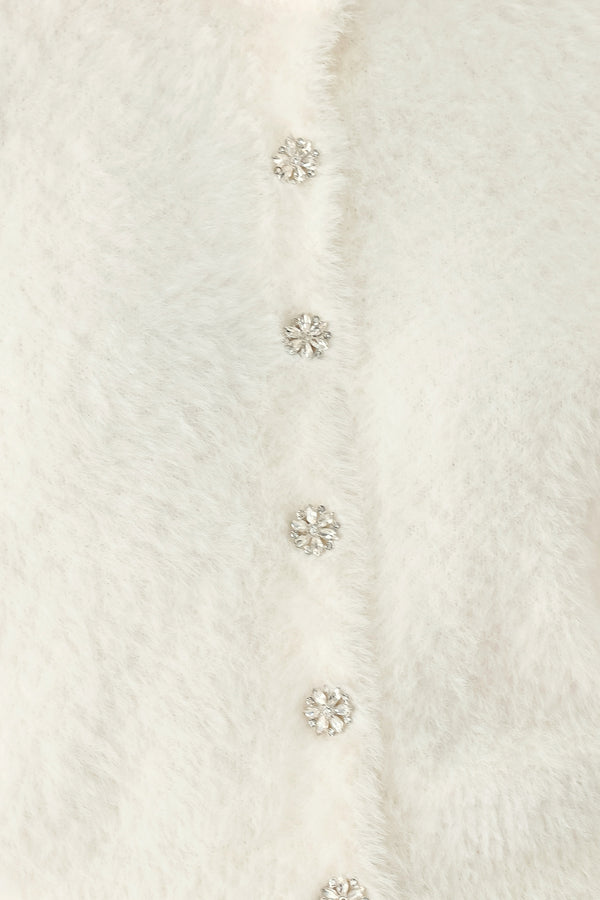 A woman wearing an off white fuzzy cropped cardigan with decorative silver buttons down the front | FREEMARKET
