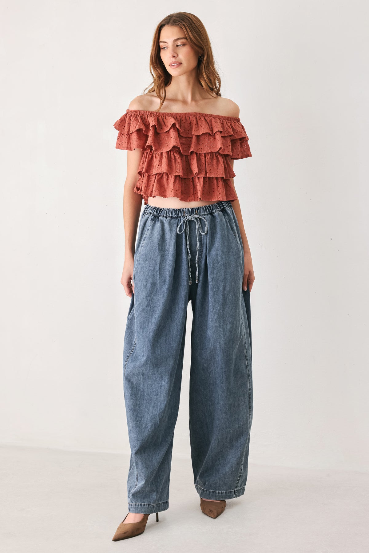 A woman wearing a terracotta-colored off-the-shoulder ruffled crop top | FREEMARKET
