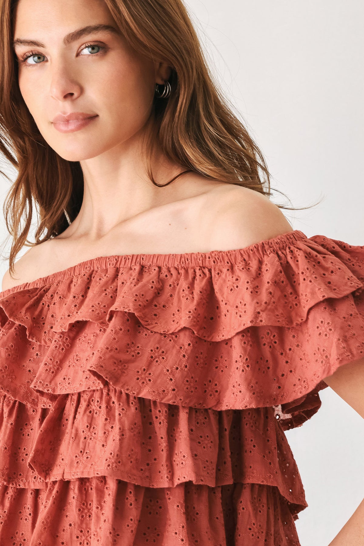 A woman wearing a terracotta-colored off-the-shoulder ruffled crop top | FREEMARKET