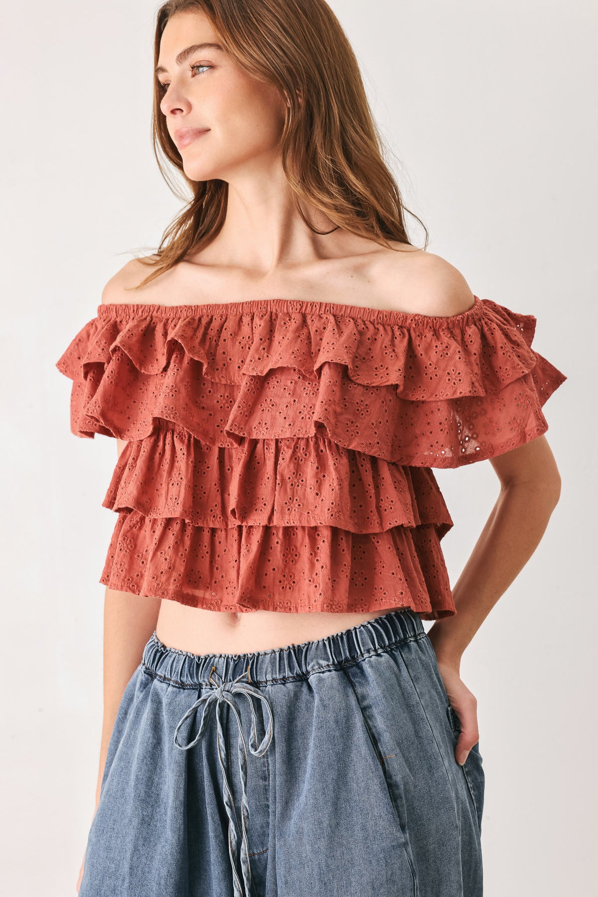 A woman wearing a terracotta-colored off-the-shoulder ruffled crop top | FREEMARKET