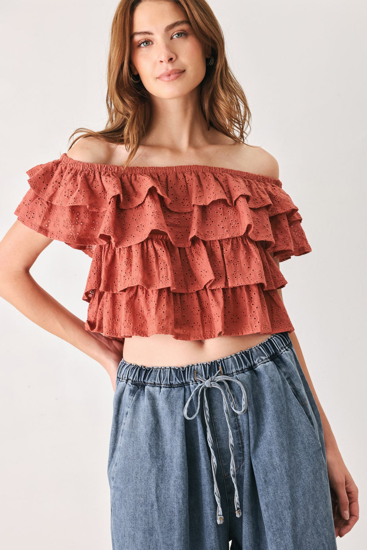 A woman wearing a terracotta-colored off-the-shoulder ruffled crop top | FREEMARKET