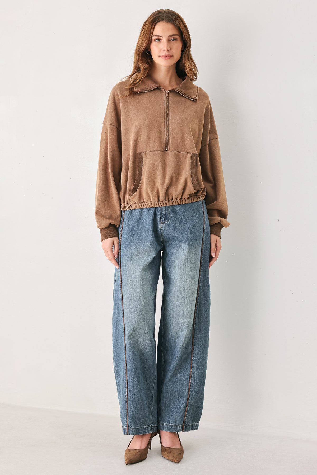 
A woman wearing a brown half-zip pullover sweatshirt with a collar and front pockets, paired with light blue jeans | FREEMARKET