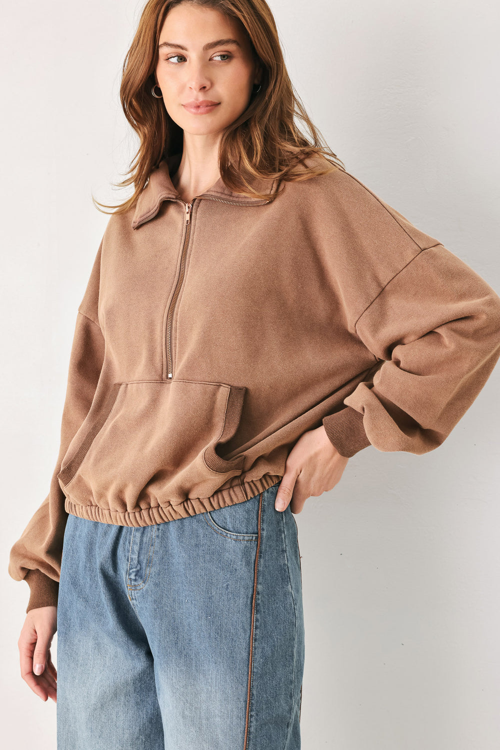 A woman wearing a brown half-zip pullover sweatshirt with a collar and front pockets, paired with light blue jeans | FREEMARKET