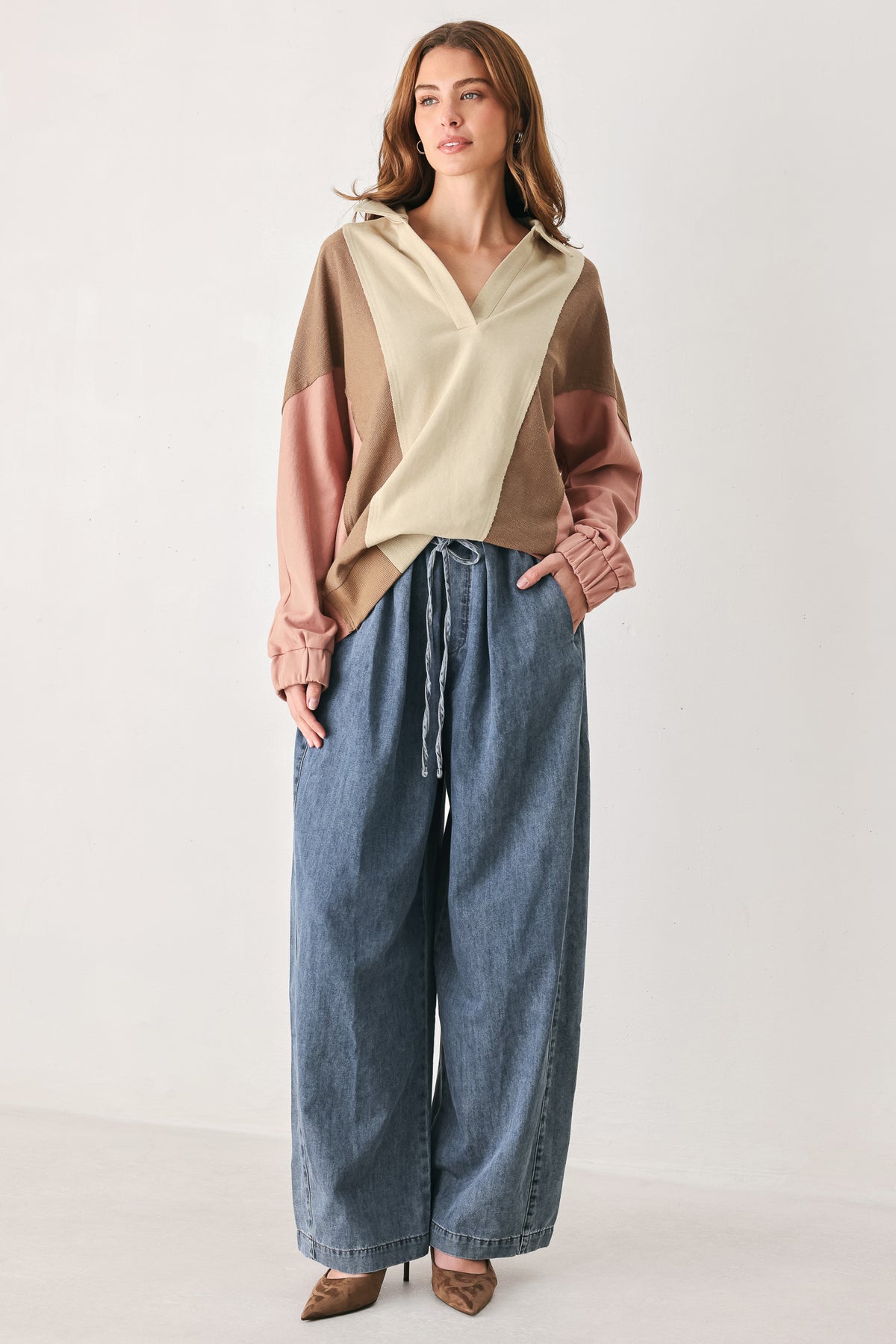 A woman wearing a color-blocked long-sleeve top with beige, cream, and dusty pink panels | FREEMARKET