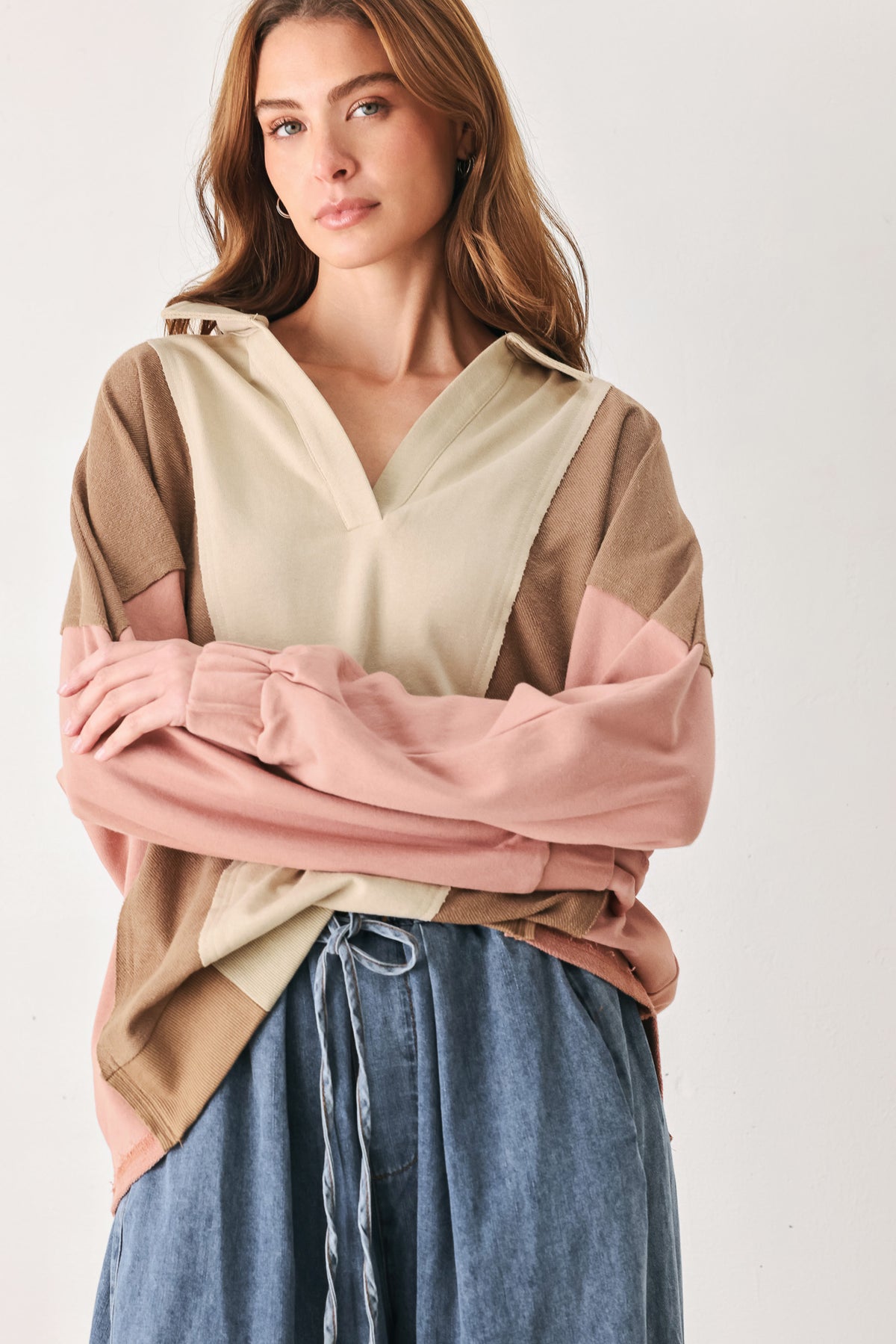 A woman wearing a color-blocked long-sleeve top with beige, cream, and dusty pink panels | FREEMARKET