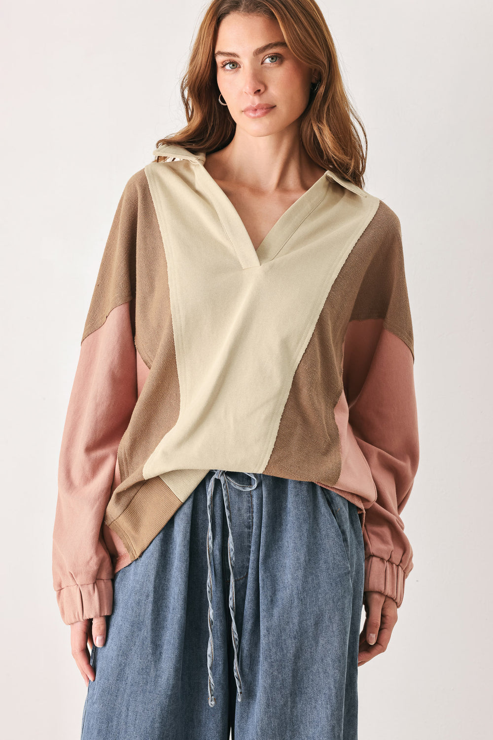 A woman wearing a color-blocked long-sleeve top with beige, cream, and dusty pink panels | FREEMARKET
