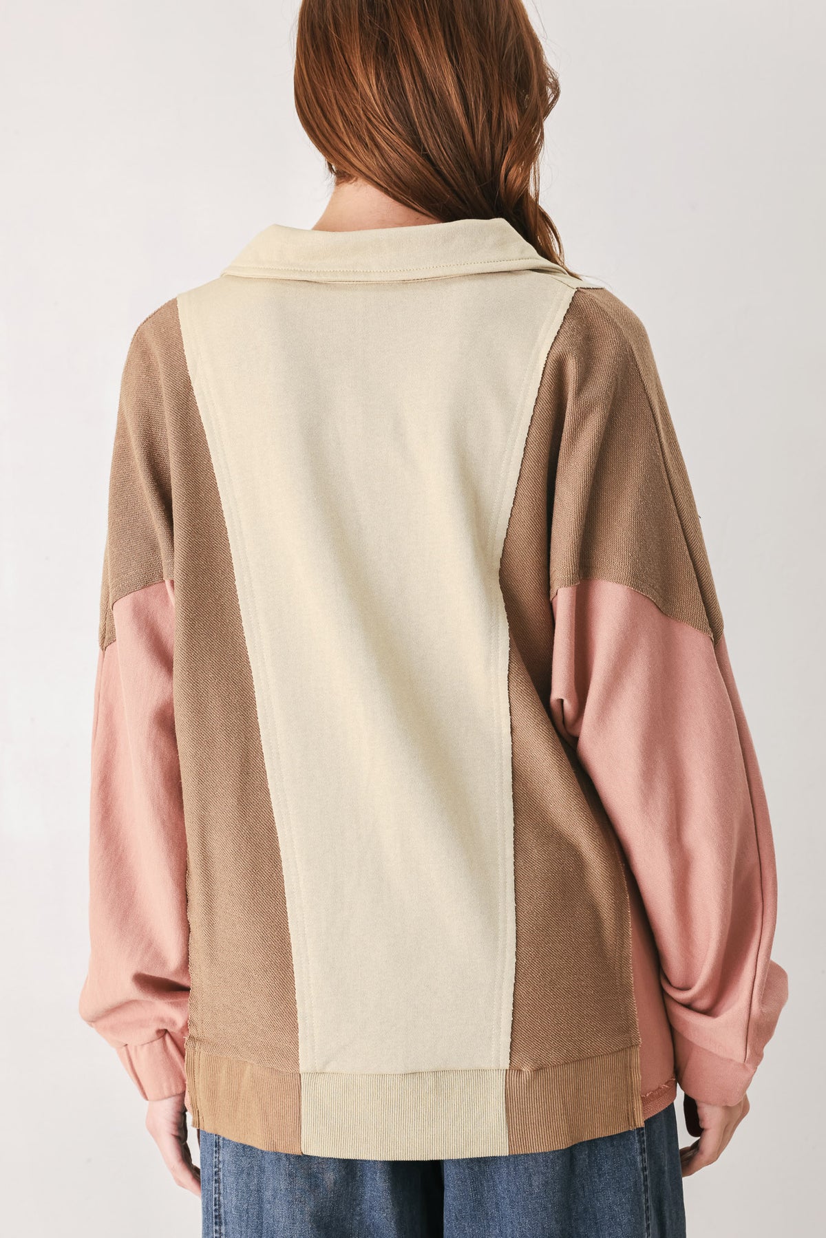 A woman wearing a color-blocked long-sleeve top with beige, cream, and dusty pink panels | FREEMARKET
