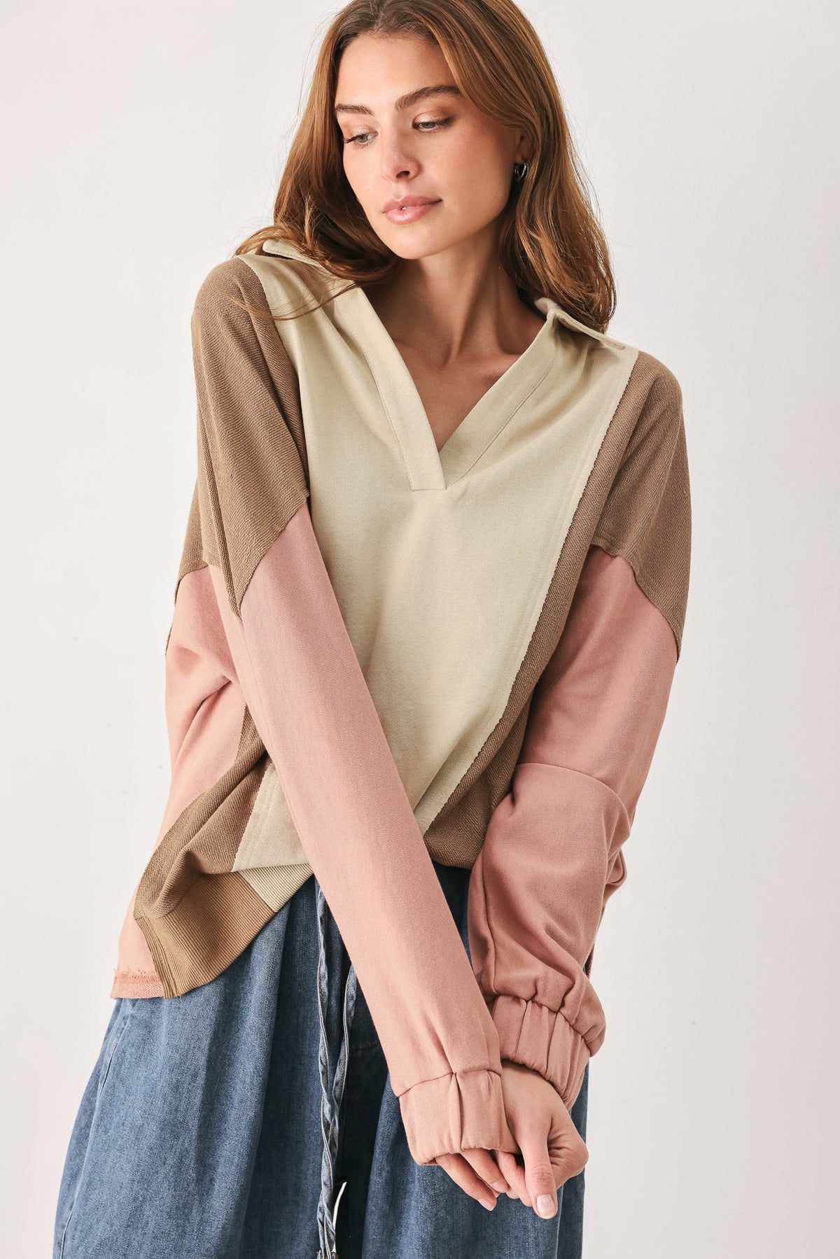 A woman wearing a color-blocked long-sleeve top with beige, cream, and dusty pink panels | FREEMARKET