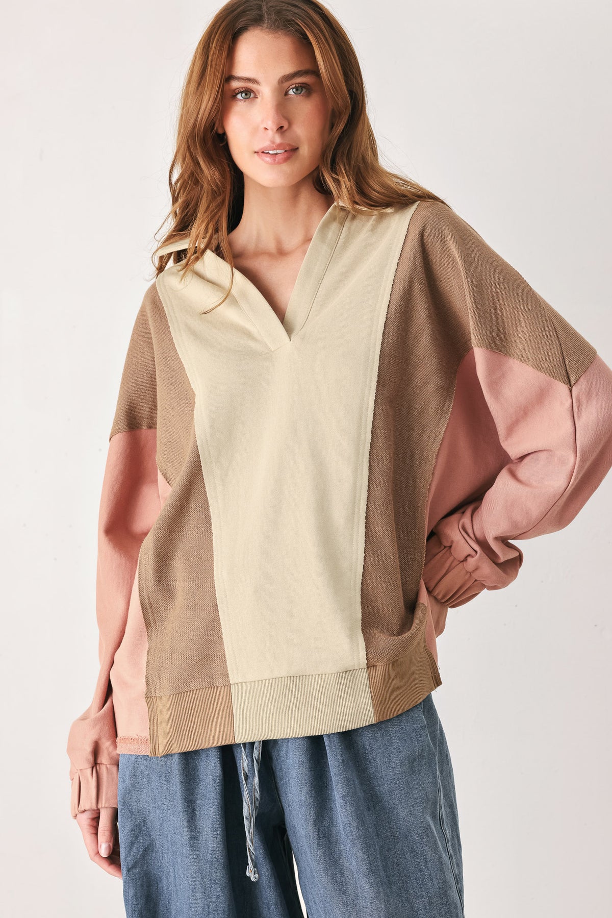 A woman wearing a color-blocked long-sleeve top with beige, cream, and dusty pink panels | FREEMARKET