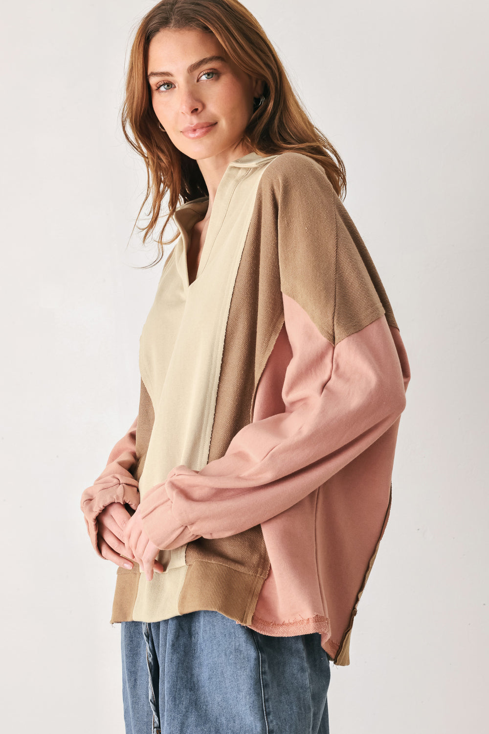 A woman wearing a color-blocked long-sleeve top with beige, cream, and dusty pink panels | FREEMARKET