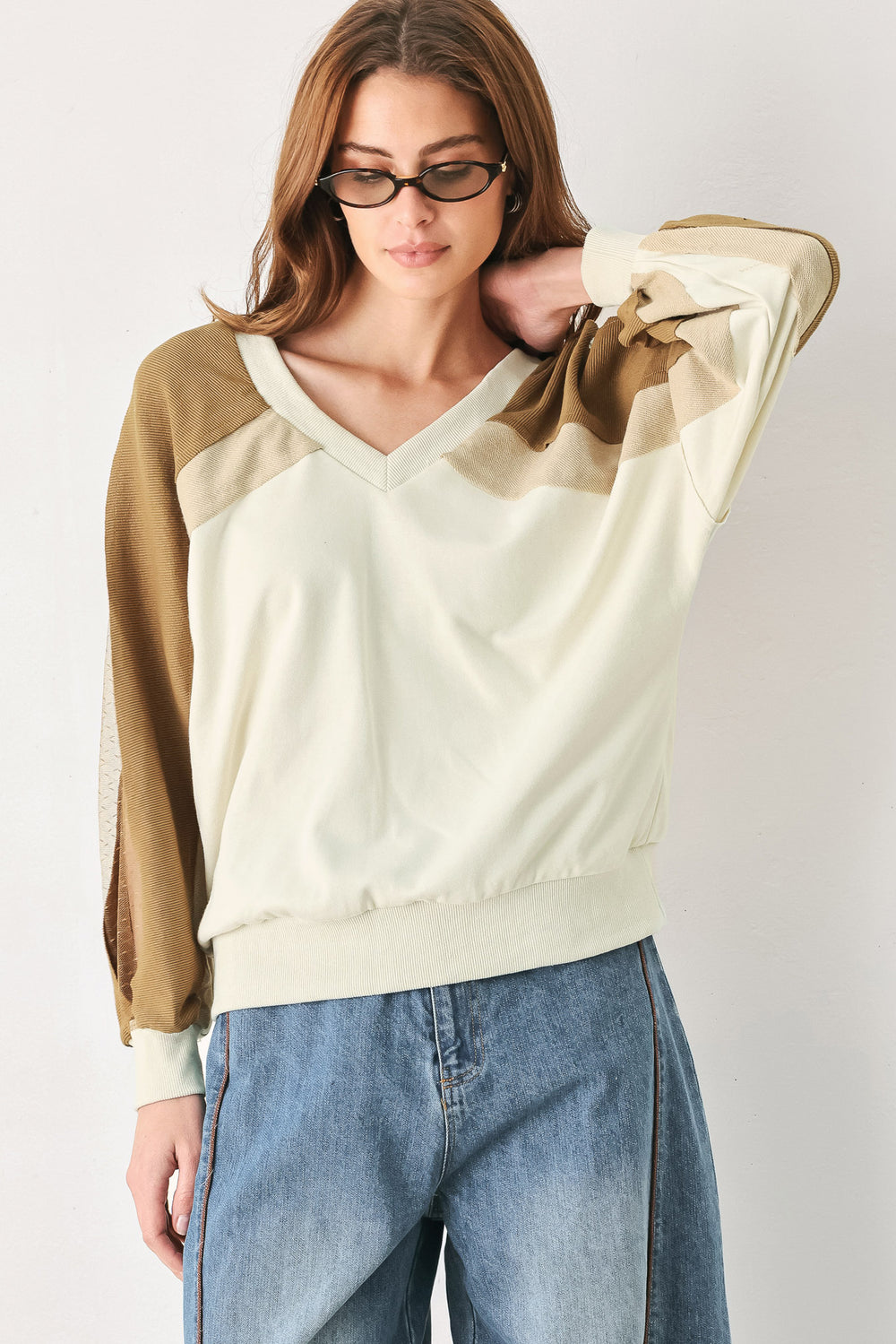 A woman wearing a color-blocked long-sleeve V-neck sweatshirt with cream and tan panels | FREEMARKET