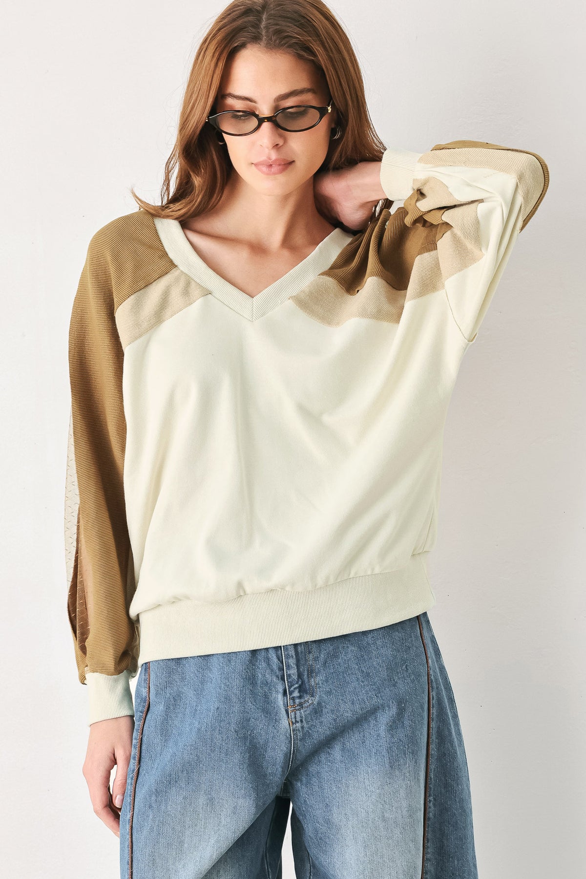 A woman wearing a color-blocked long-sleeve V-neck sweatshirt with cream and tan panels | FREEMARKET