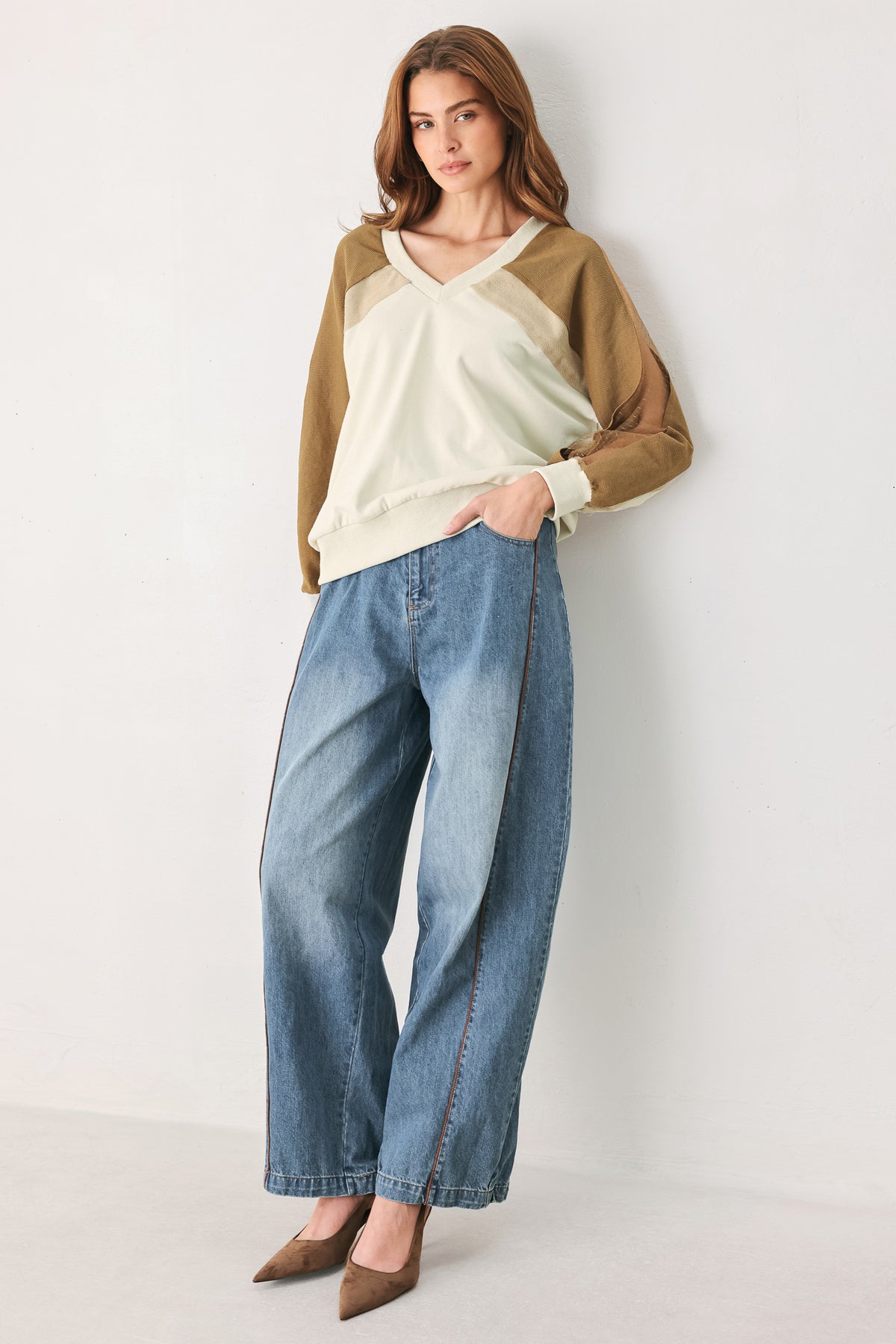 A woman wearing a color-blocked long-sleeve V-neck sweatshirt with cream and tan panels | FREEMARKET