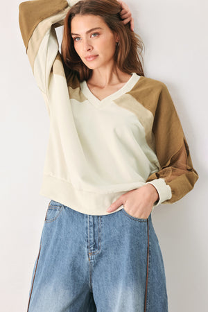 A woman wearing a color-blocked long-sleeve V-neck sweatshirt with cream and tan panels | FREEMARKET
