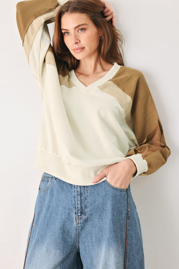 A woman wearing a color-blocked long-sleeve V-neck sweatshirt with cream and tan panels | FREEMARKET
