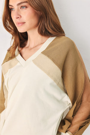 A woman wearing a color-blocked long-sleeve V-neck sweatshirt with cream and tan panels | FREEMARKET