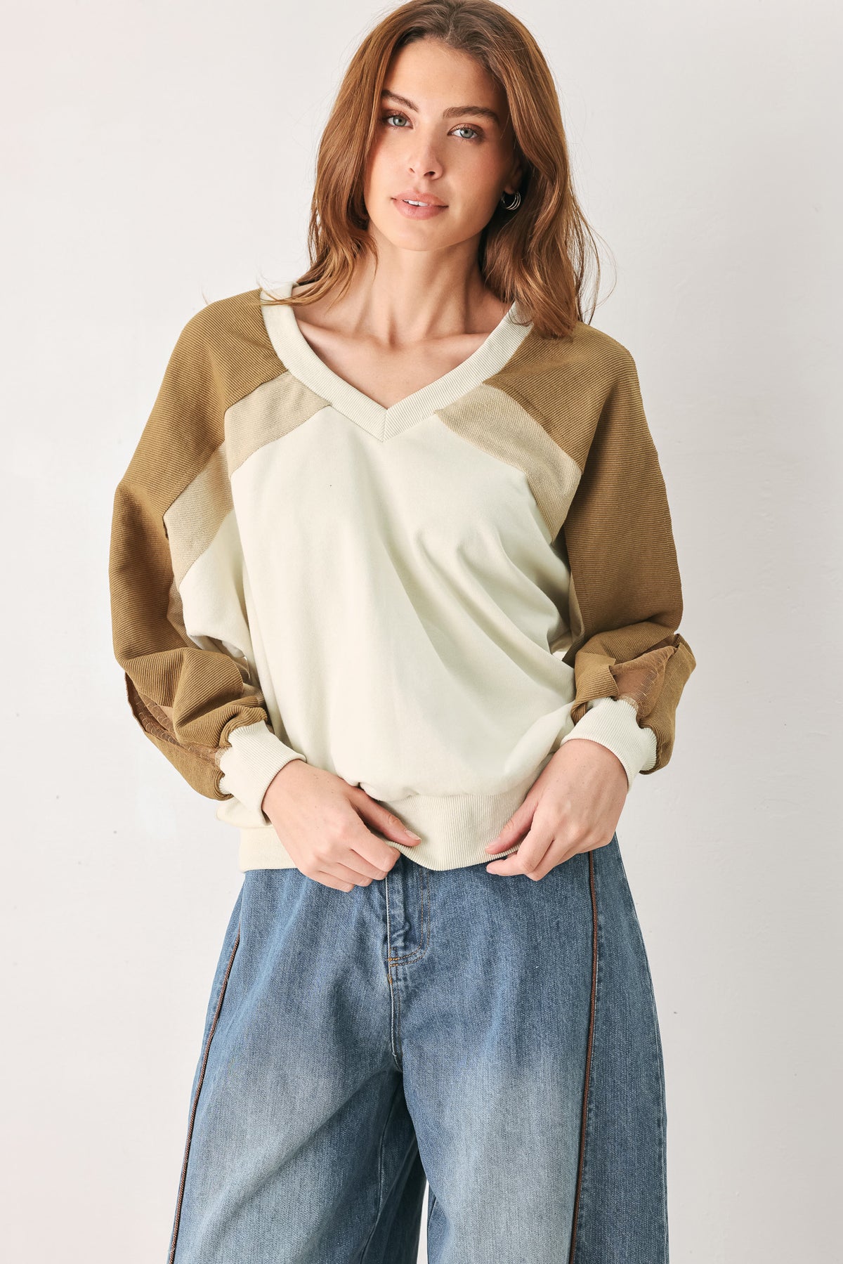 A woman wearing a color-blocked long-sleeve V-neck sweatshirt with cream and tan panels | FREEMARKET