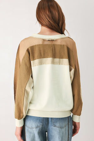 A woman wearing a color-blocked long-sleeve V-neck sweatshirt with cream and tan panels | FREEMARKET