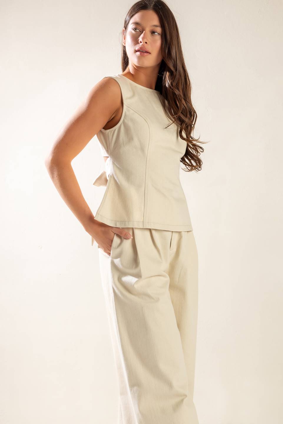 A solid twill top featuring round neckline, sleeveless, back cut out and button/tie closure.