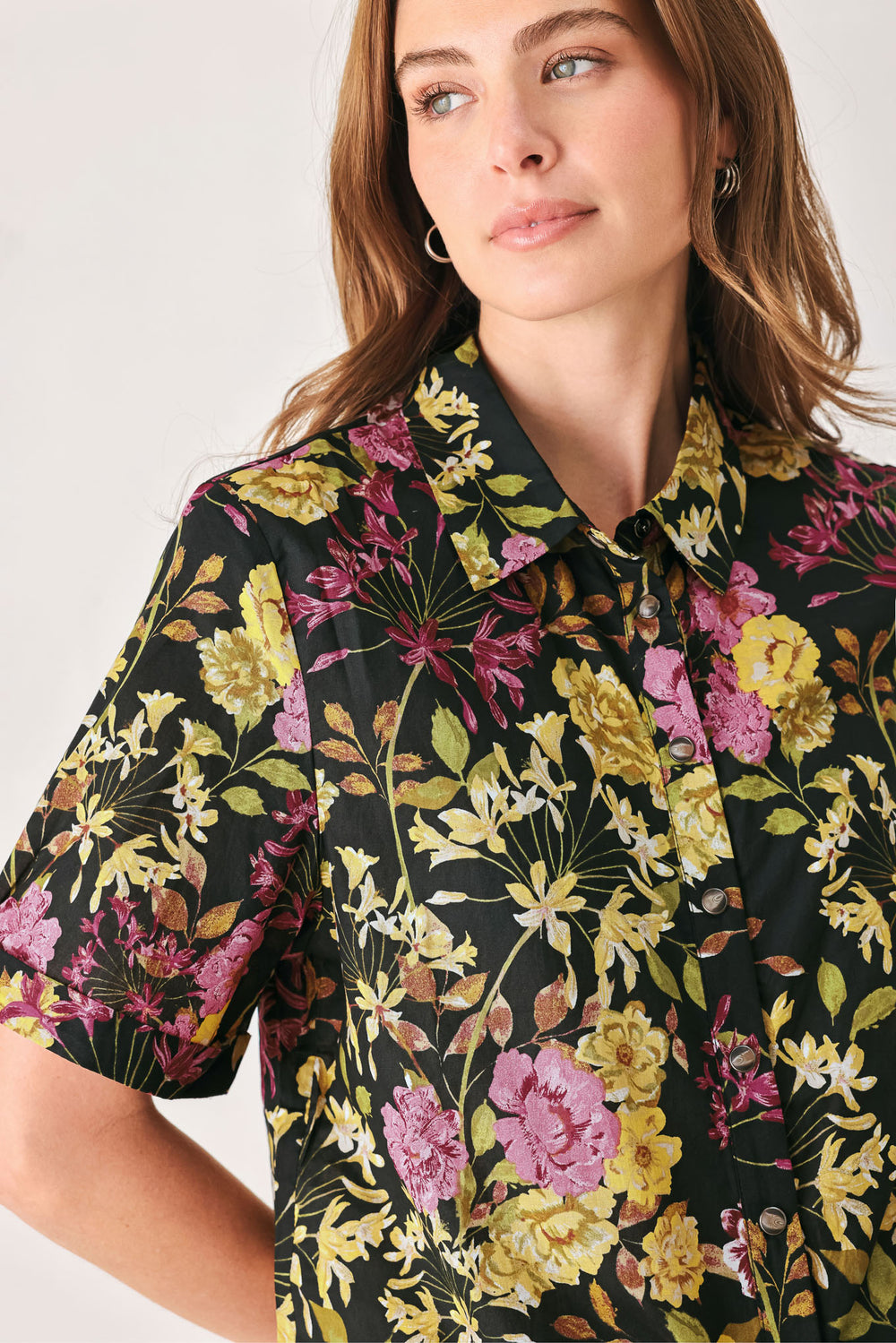 A woman wearing a black short-sleeve button-up shirt with a vibrant multicolor floral print in pink, yellow, and green | FREEMARKET