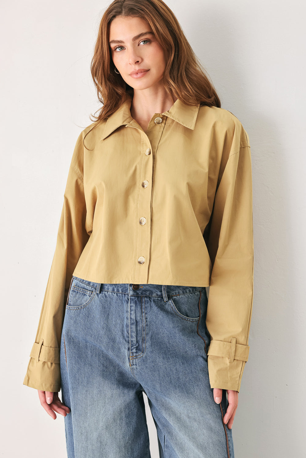 A woman wearing a camel tan button-up shirt with a pointed collar and brown-tone buttons | FREEMARKET
