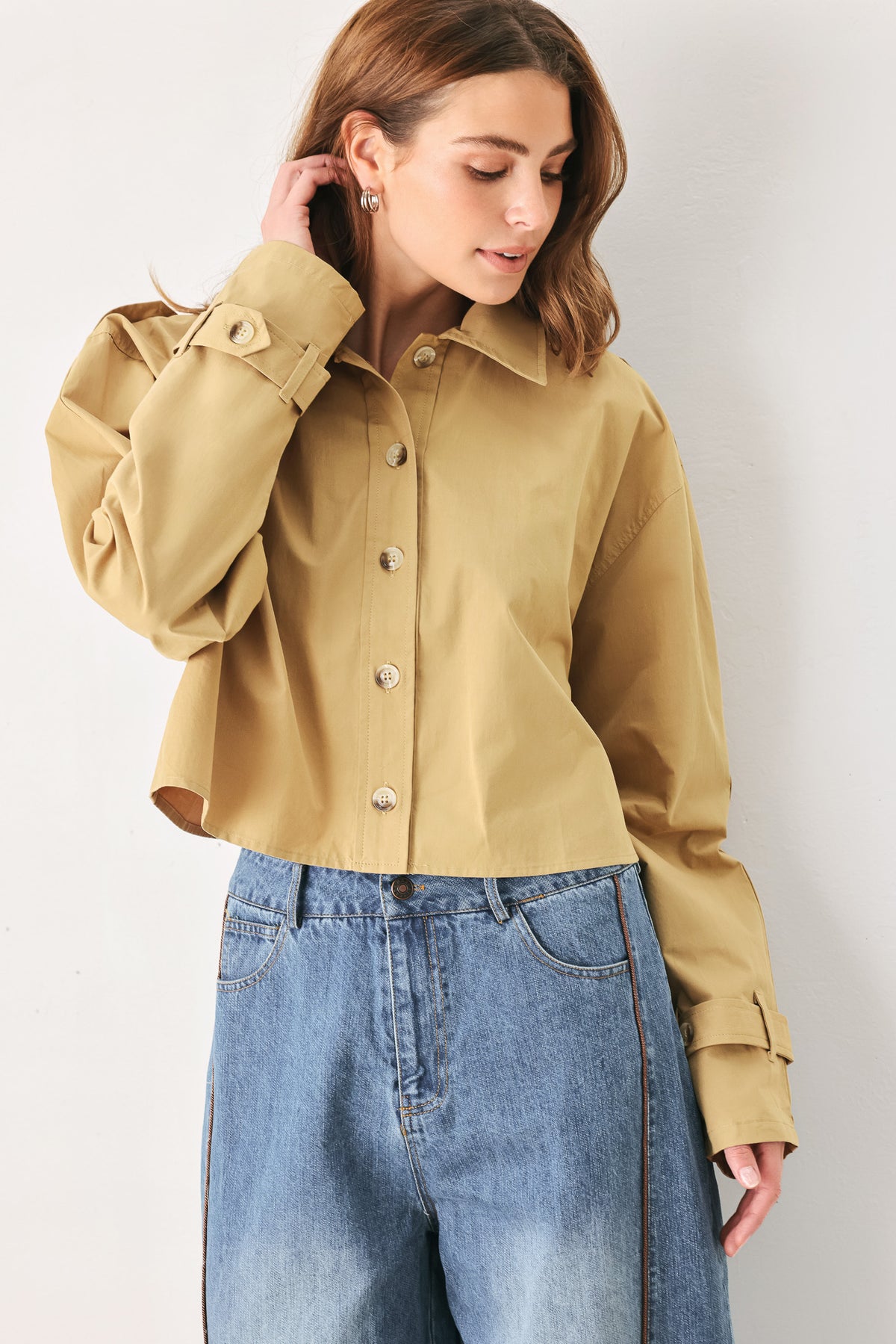 A woman wearing a camel tan button-up shirt with a pointed collar and brown-tone buttons | FREEMARKET
