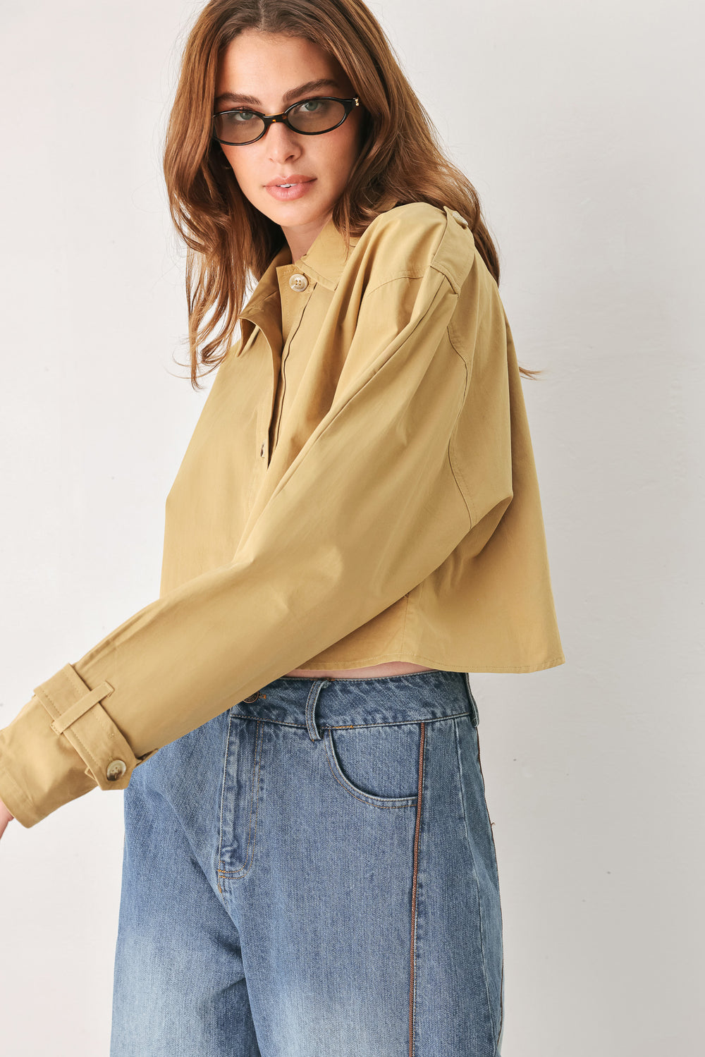 A woman wearing a camel tan button-up shirt with a pointed collar and brown-tone buttons | FREEMARKET