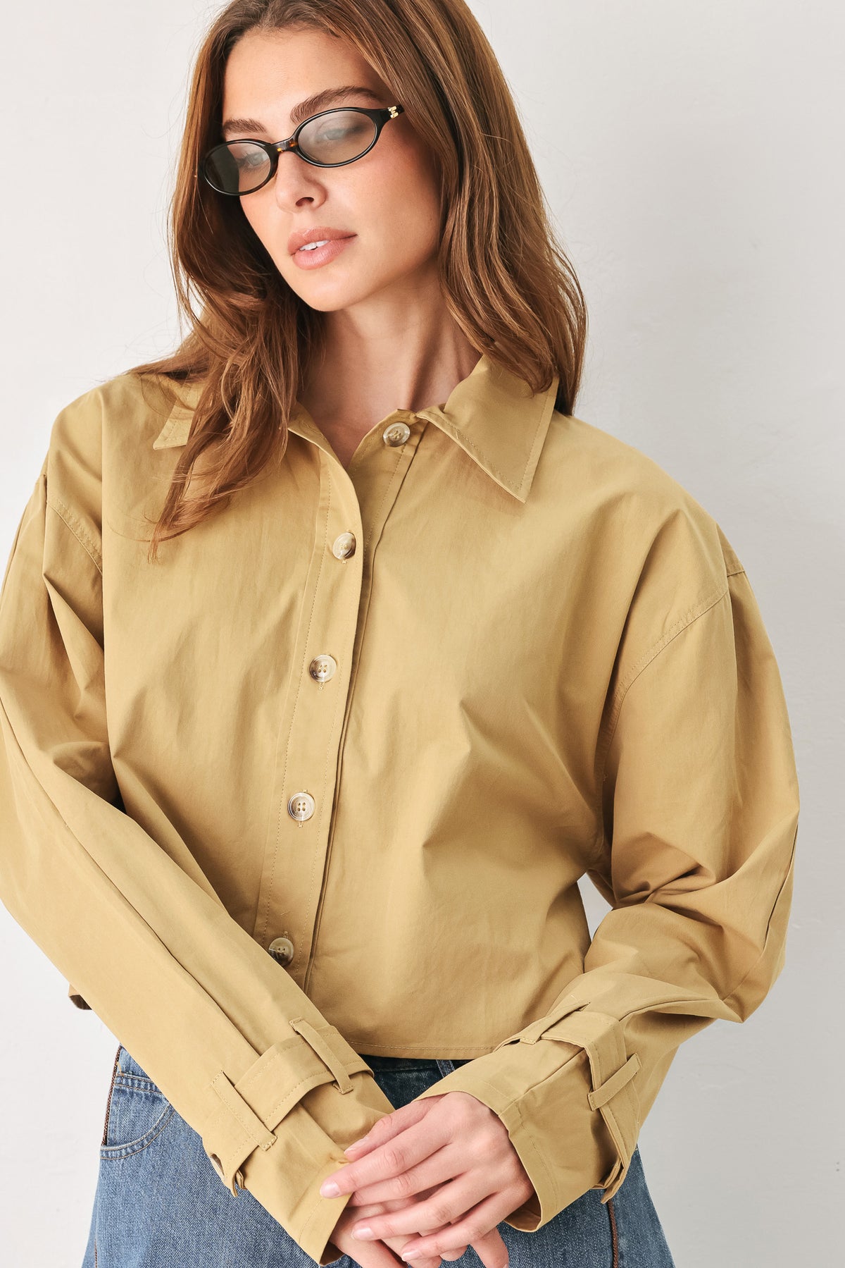 A woman wearing a camel tan button-up shirt with a pointed collar and brown-tone buttons | FREEMARKET
