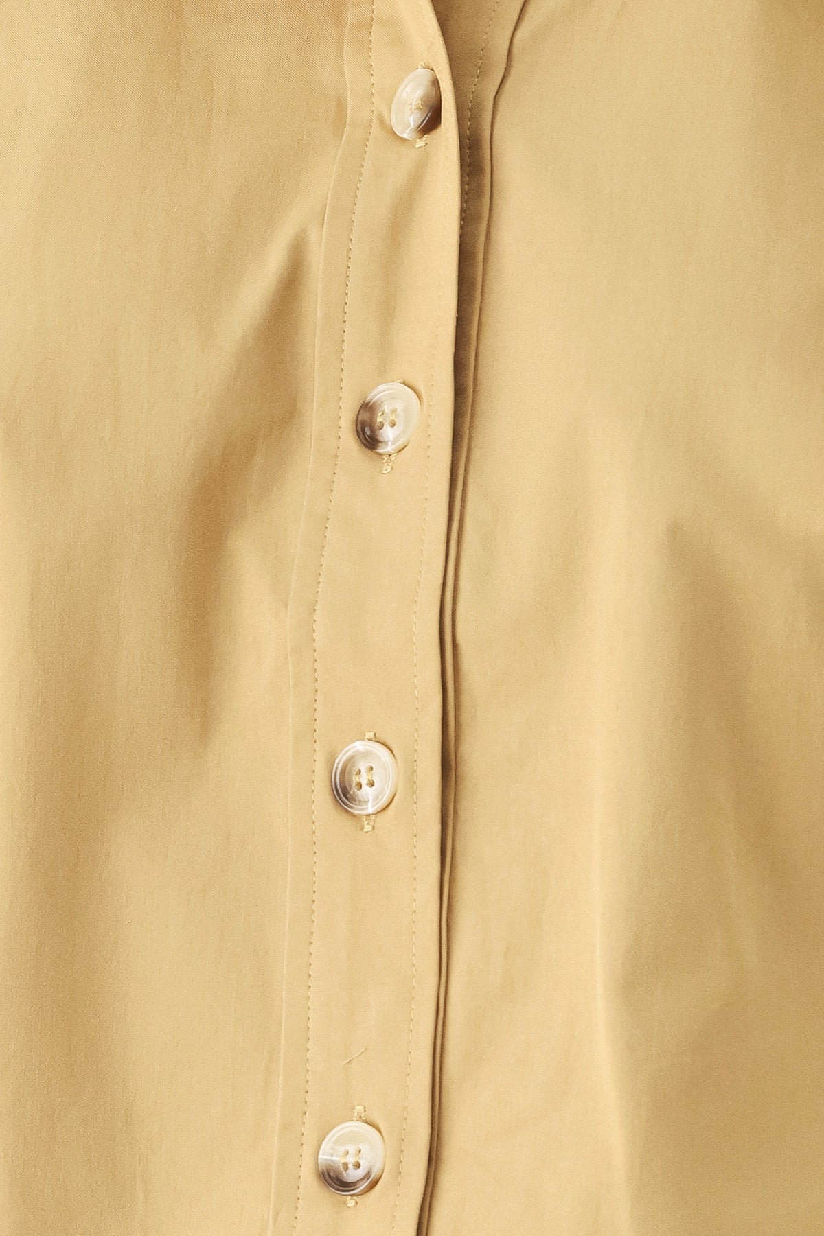 A woman wearing a camel tan button-up shirt with a pointed collar and brown-tone buttons | FREEMARKET