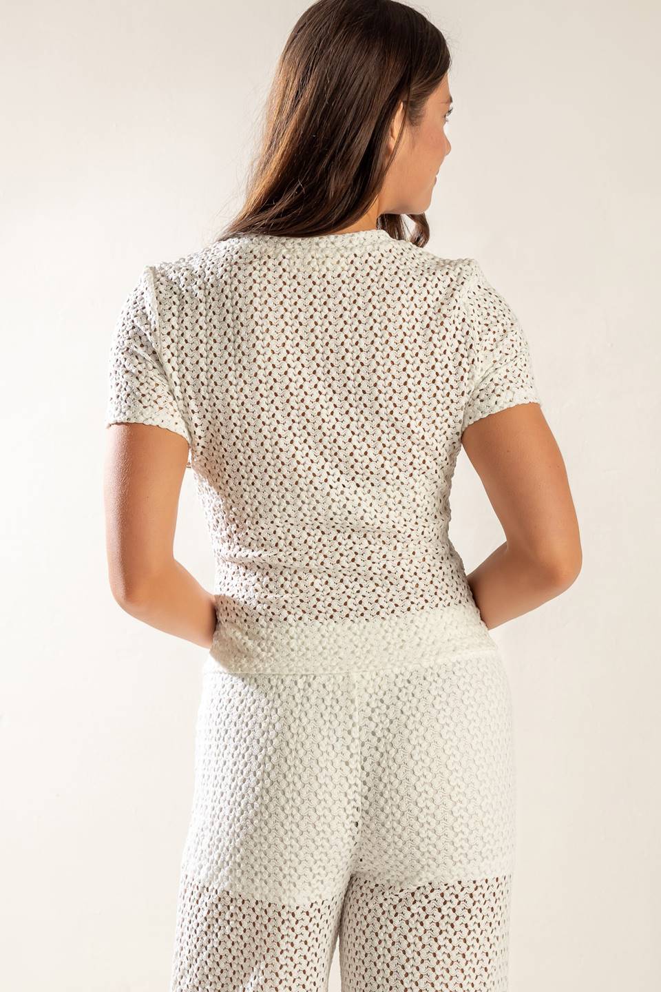 A white knit top with a round neckline, featuring short sleeves and a semi-sheer design