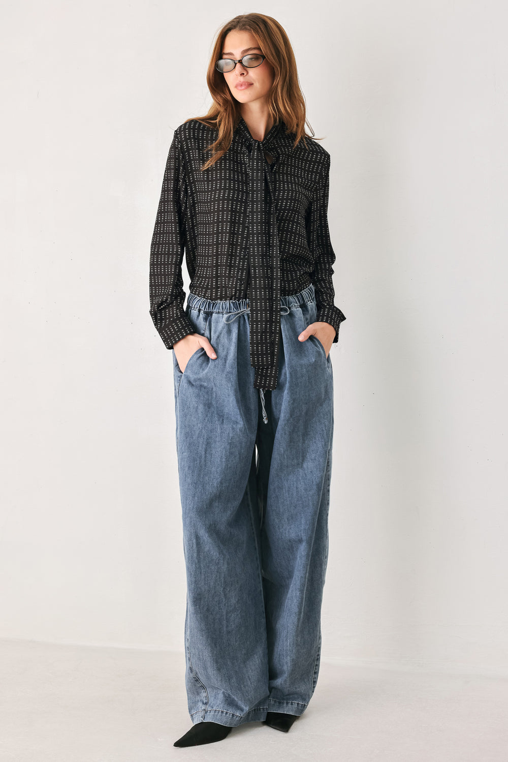 Person wearing a shirt with the word "FREE" printed on and wide-leg jeans on a plain background | FREEMARKET