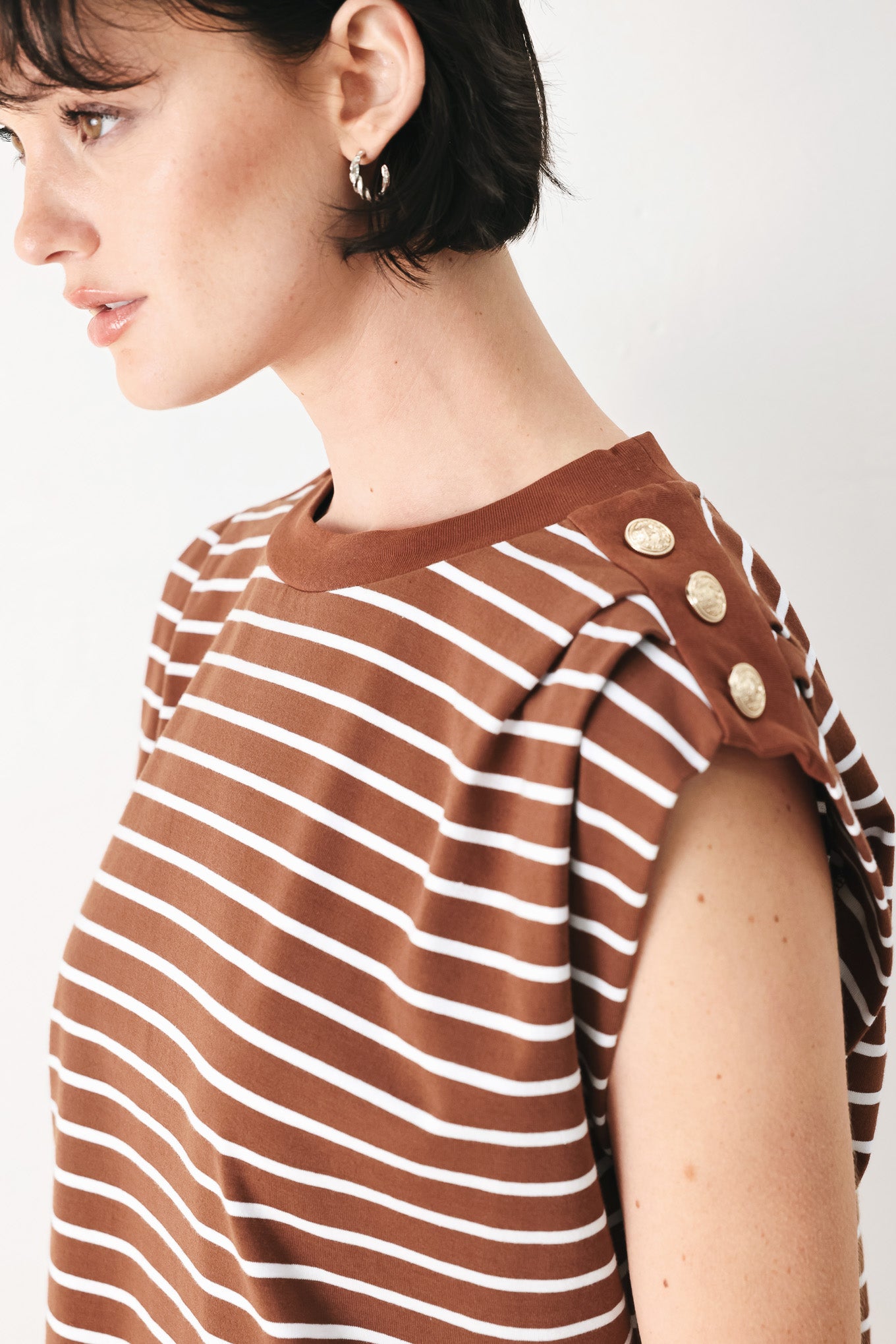 Woman wearing a brown and white striped knit top with crew neckline, sleeveless and should button detail | FREEMARKET
