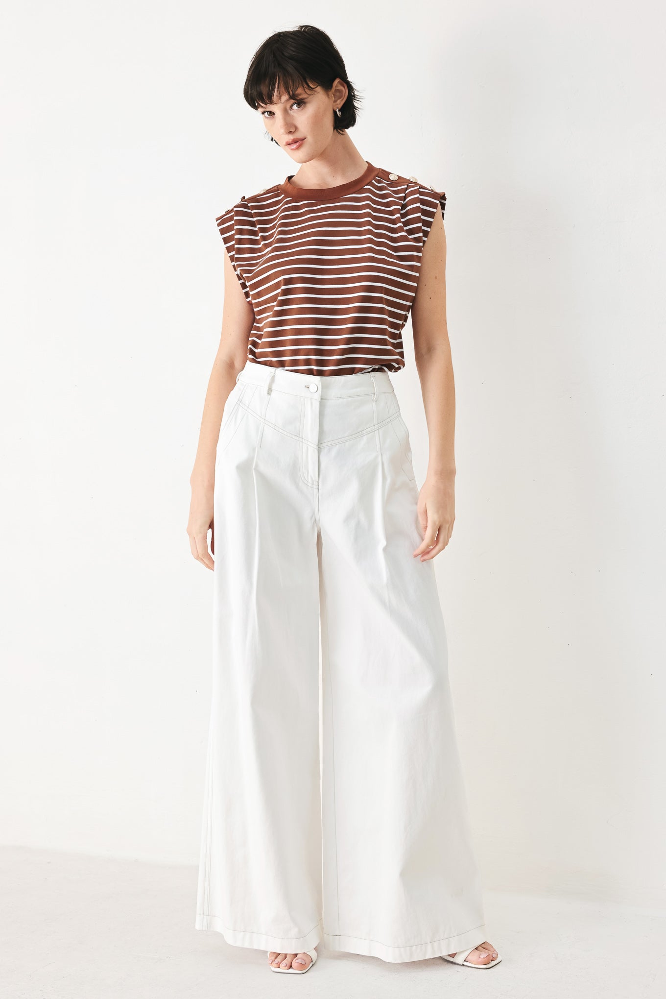 Woman wearing a brown and white striped knit top with crew neckline, sleeveless and should button detail | FREEMARKET