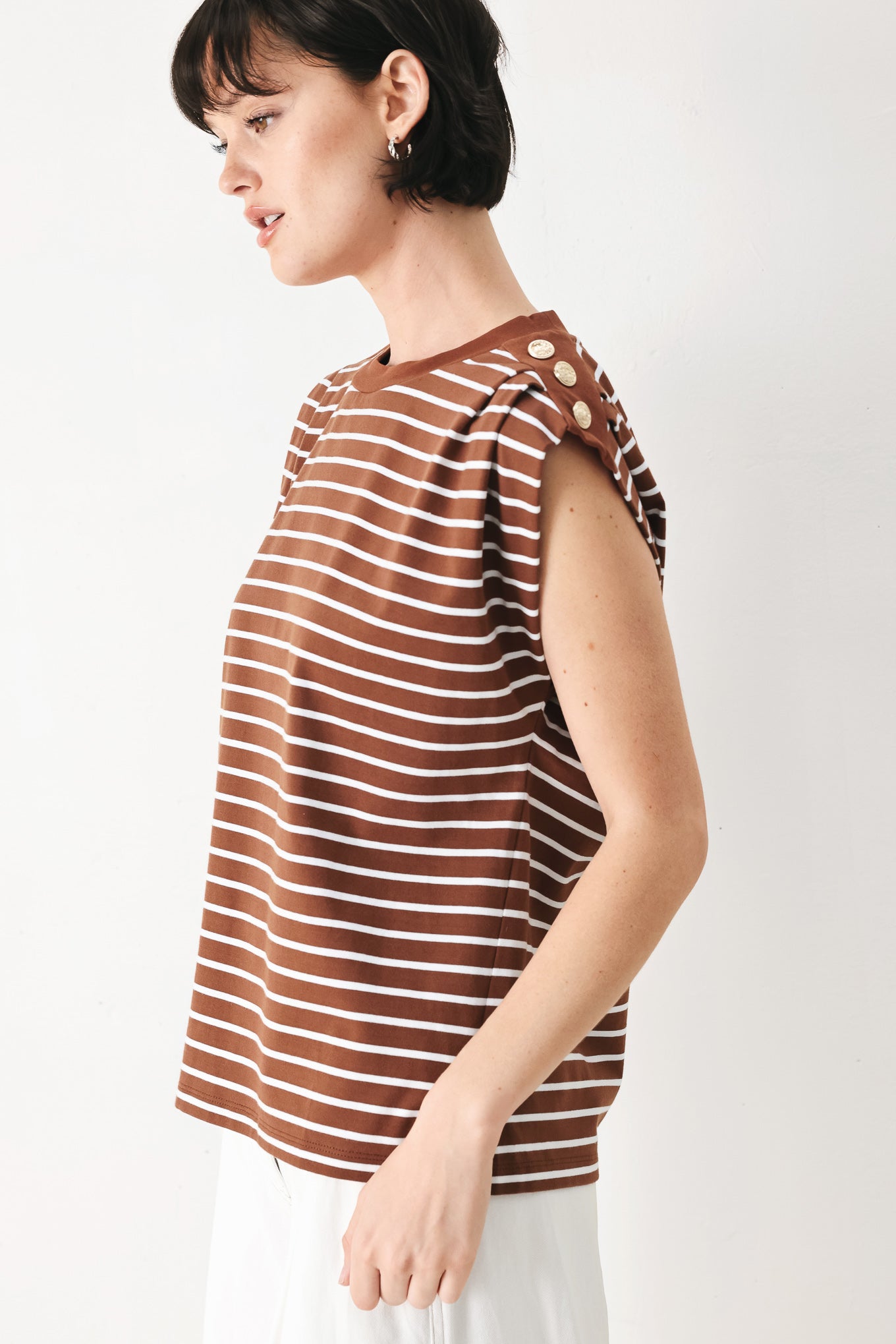 Woman wearing a brown and white striped knit top with crew neckline, sleeveless and should button detail | FREEMARKET