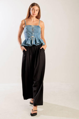 A washed denim top featuring a straight neckline, straps, front lace up detail, peplum and back zipper closure.