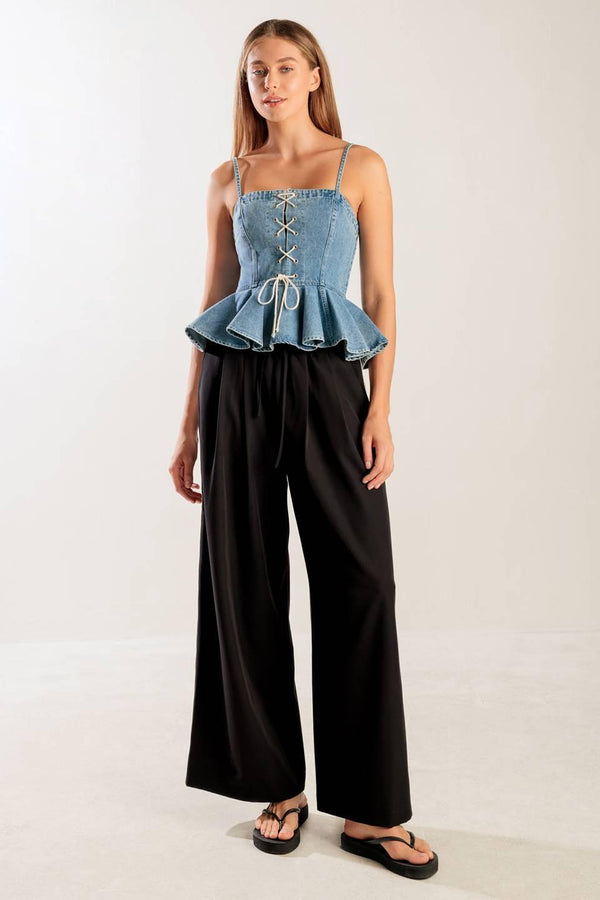 A washed denim top featuring a straight neckline, straps, front lace up detail, peplum and back zipper closure.