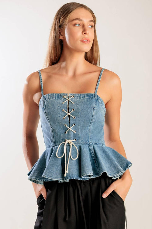 A washed denim top featuring a straight neckline, straps, front lace up detail, peplum and back zipper closure.