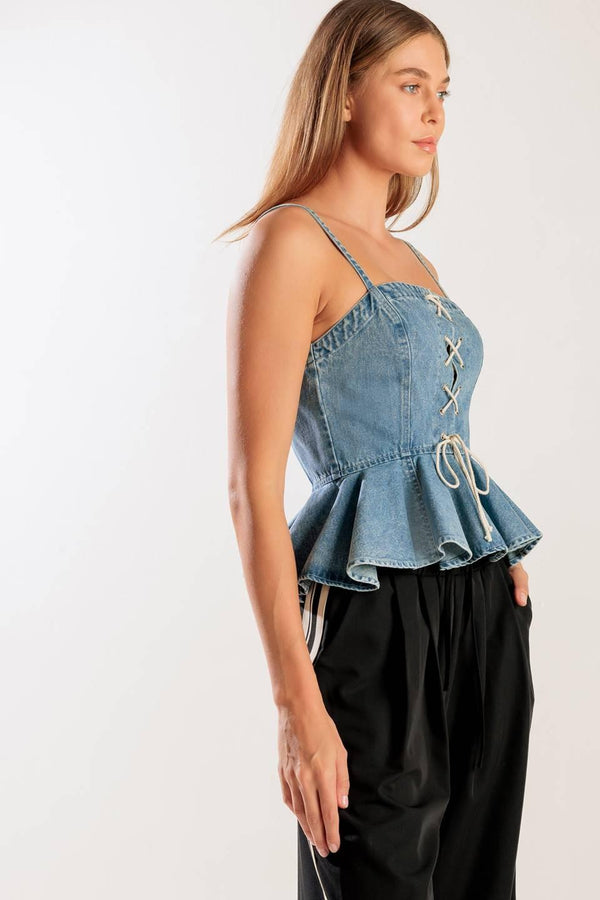A washed denim top featuring a straight neckline, straps, front lace up detail, peplum and back zipper closure.