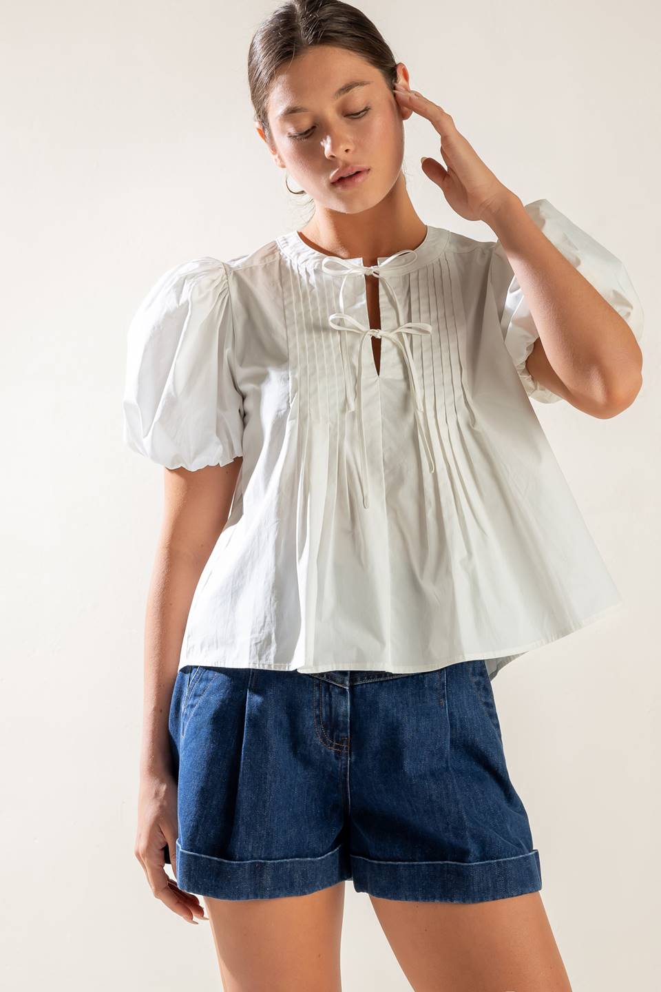 A solid white woven top featuring collar, button down and short puff sleeve.