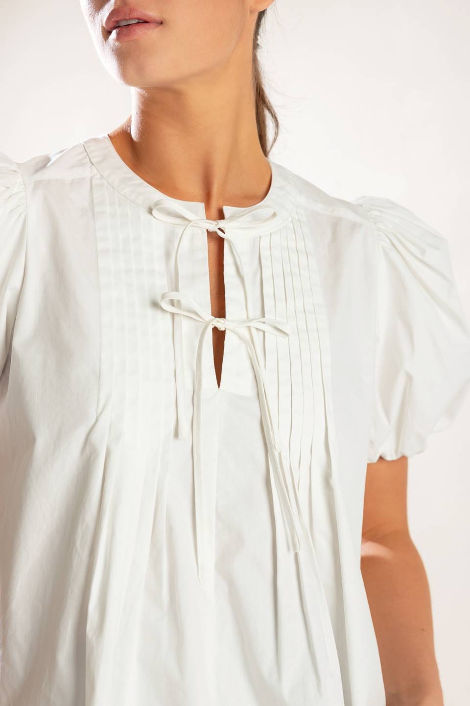 A solid white woven top featuring collar, button down and short puff sleeve.