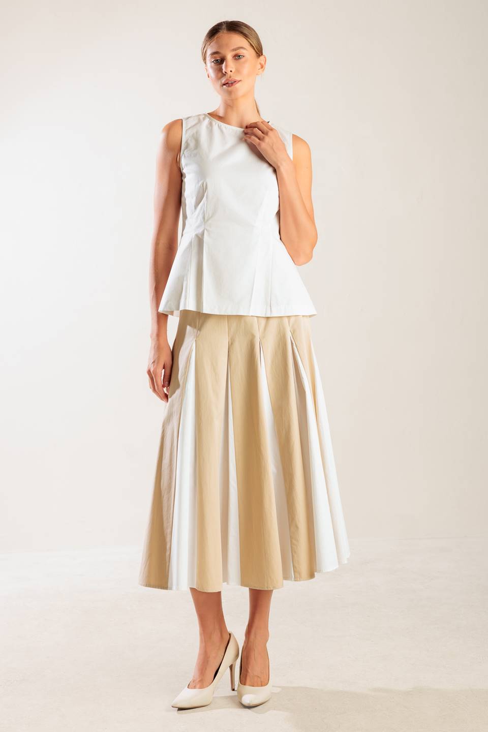 A solid, sleeveless, white woven top featuring round neckline and peplum