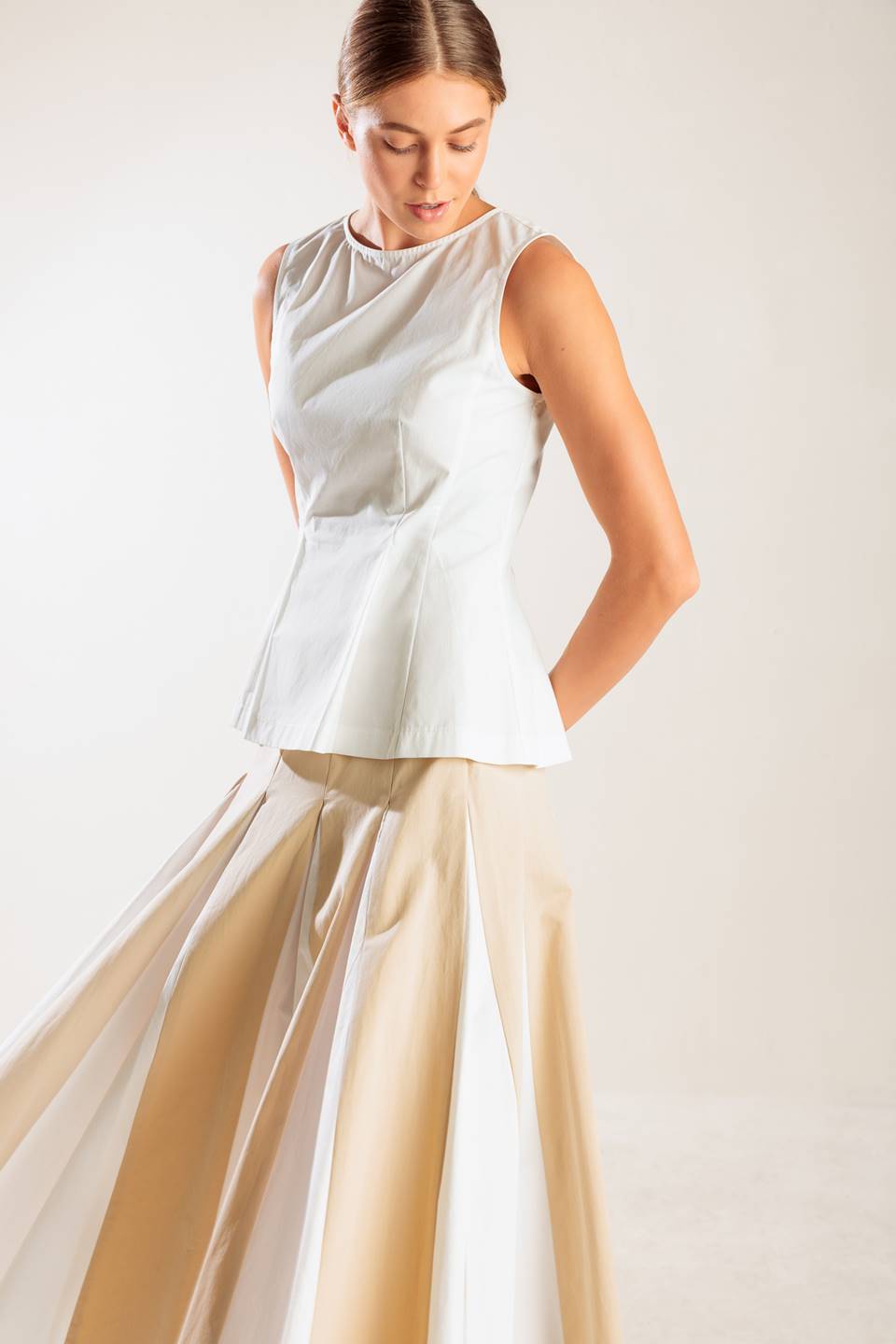 A solid, sleeveless, white woven top featuring round neckline and peplum