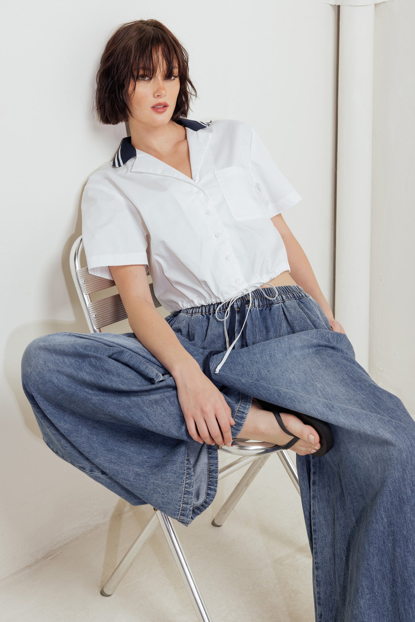 A woven crop top featuring contrasting collar, button down and waist drawstring.